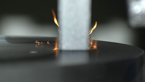 Close up image of a surface grinder grinding wheel spinning against a rotary grinding table producing sparks